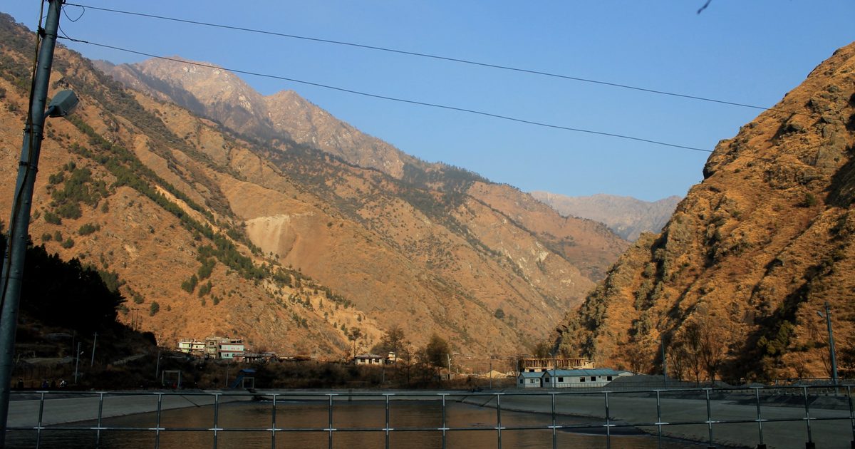 A run-of-river hydropower site in a Himalayan valley in Nepal, with the forebay basin and project buildings in the foreground
