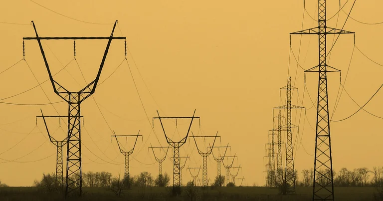 High-voltage transmission towers silhouetted at sunset, the kind of national grid infrastructure private power traders can now pay to use under ERC's open-access rules