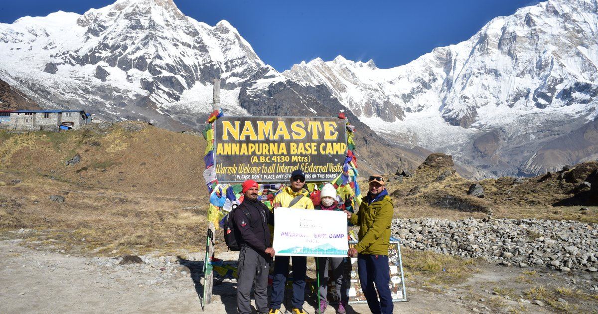 Two trekkers posing at Annapurna Base Camp in Nepal with Himalayan peaks behind them