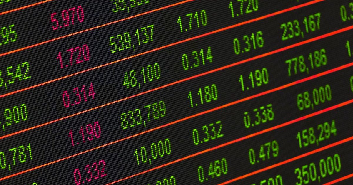 A stock market ticker board flashing red and green price quotes
