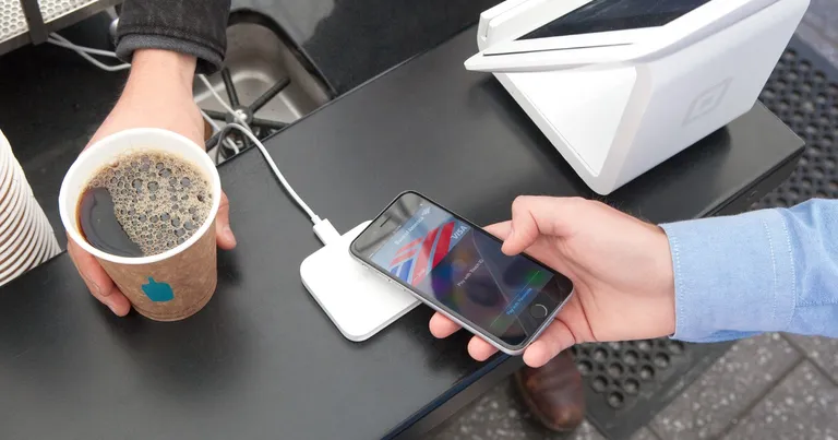 An iPhone held over a card reader paying with Apple Pay through a Visa card, the kind of tap-to-pay checkout NIC Asia Bank now lets its merchants accept